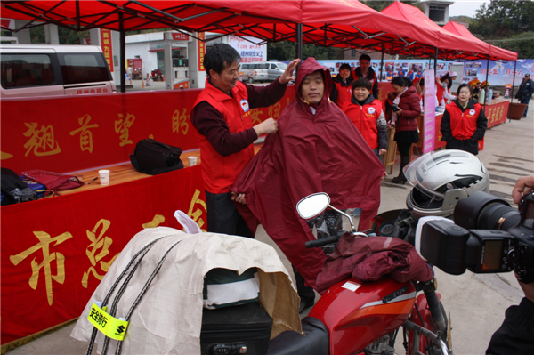 梧州市總工會(huì)的黨員義工們?cè)谑袞|出口春運(yùn)服務(wù)站助力“摩托大軍”平安返鄉(xiāng)，幫助他們檢查車輛和行李，穿上雨衣。--黃賀峰攝.j